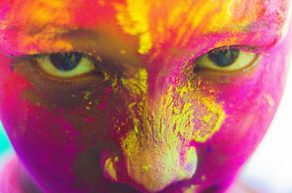Colorful close-up portrait of a child celebrating Holi in Kochi, India with vibrant face paint.