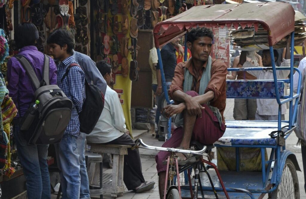 Vibrant Indian street market scene with rickshaw and people shopping.
